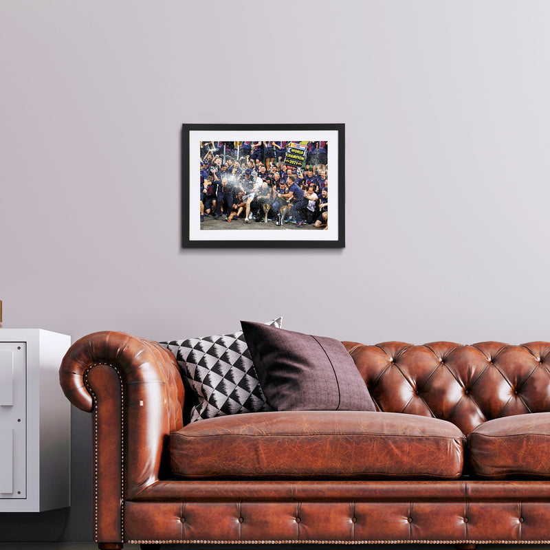 Picture hung on the wall over couch of Max Verstappen in a crowd celebrating when he became a World Champion. 